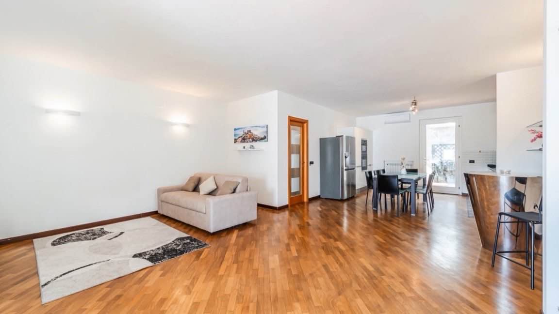 Primo fotogramma dell'Home Tour: il soggiorno con il parquet e la luce che arriva dalla terrazza.
