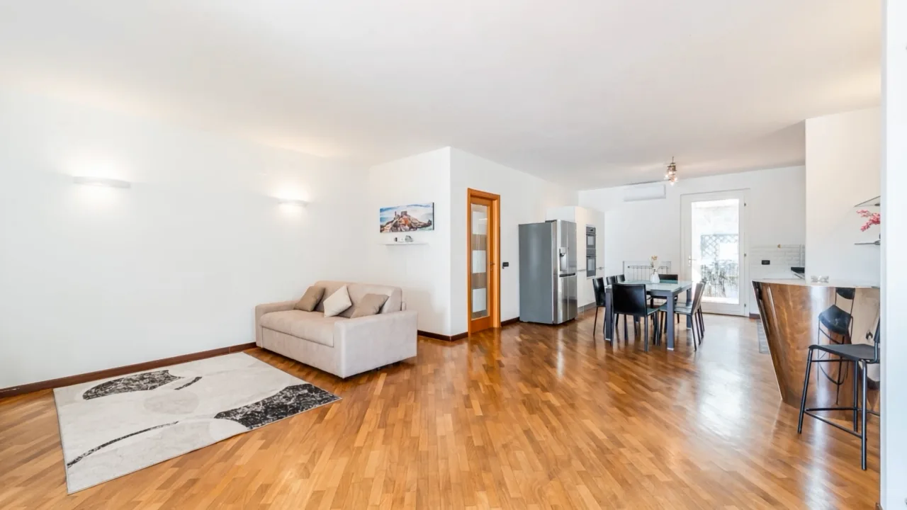 Primo fotogramma dell'Home Tour: il soggiorno con il parquet e la luce che arriva dalla terrazza.
